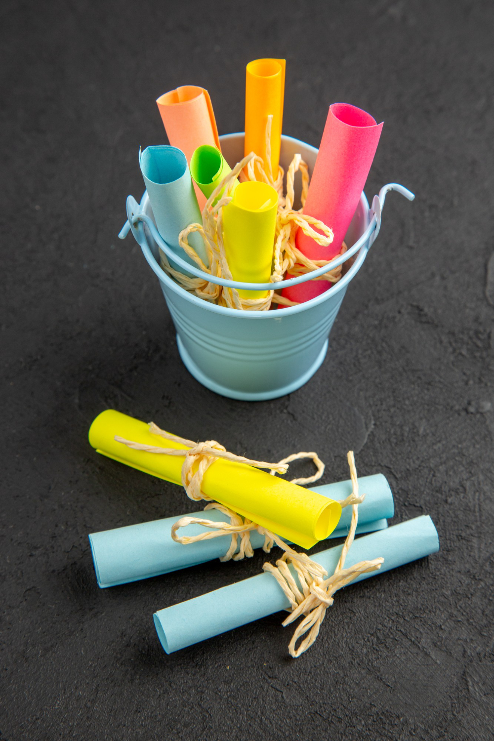 bottom-view-colored-note-papers-rolled-up-sticky-notes-tied-with-rope-small-bucket-black-table